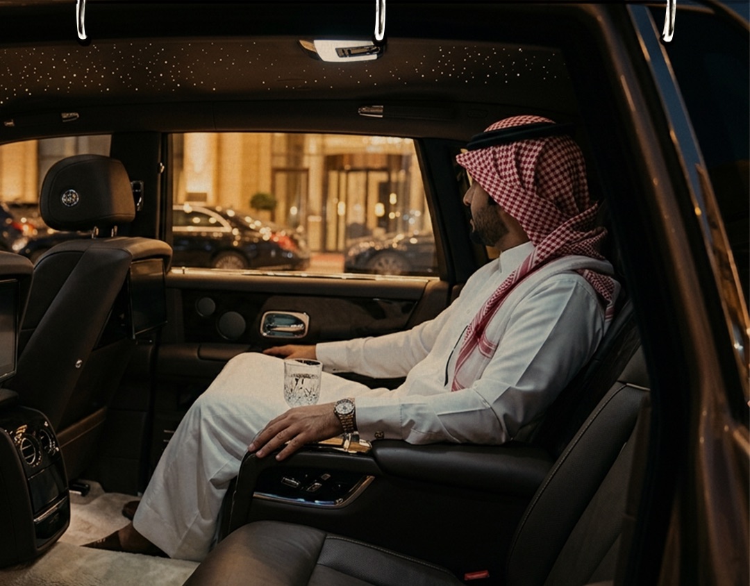 An executive seated in the rear of his own chauffeured car at night in Riyadh
